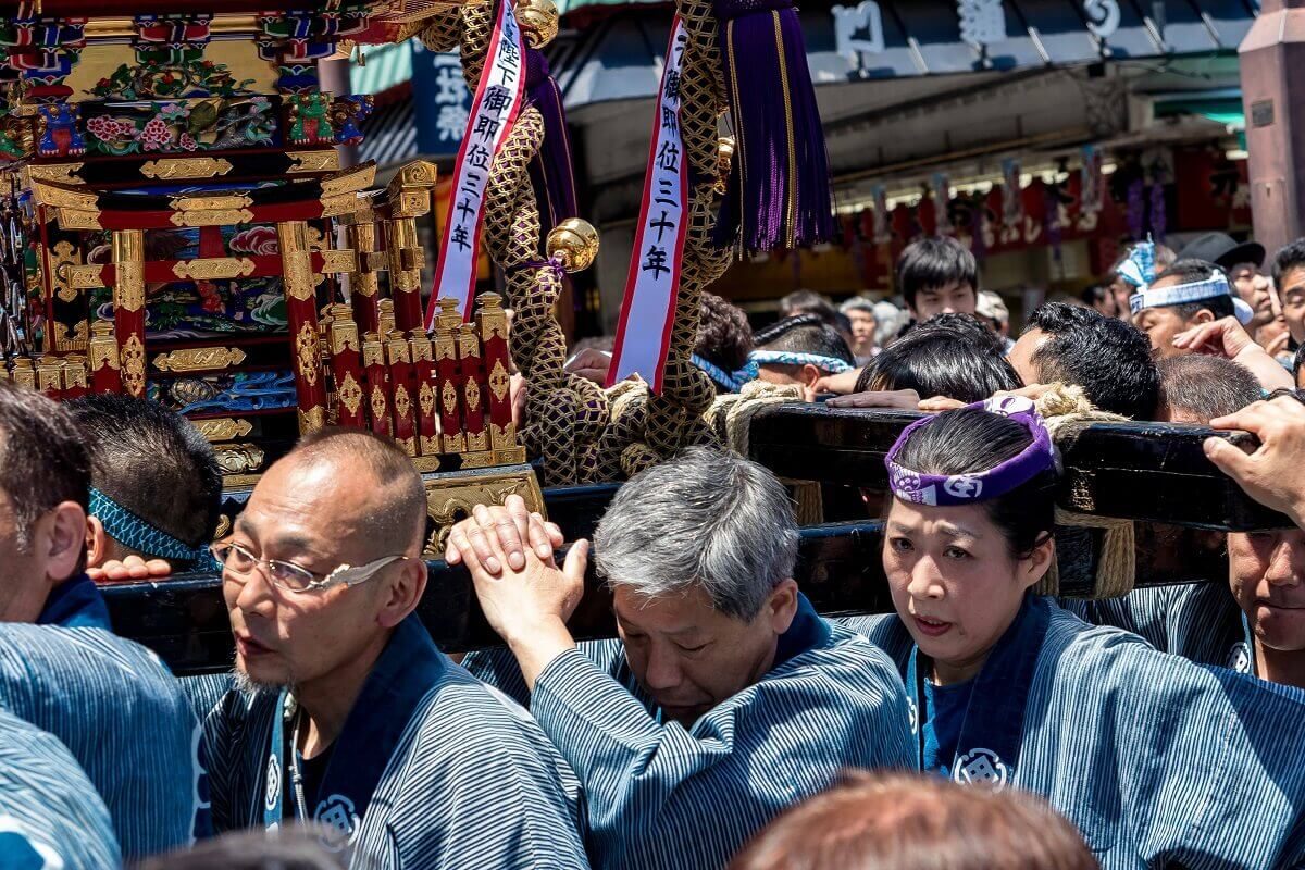 Menschen tragen einen Mikoshi durch die Straßen von Tokyo